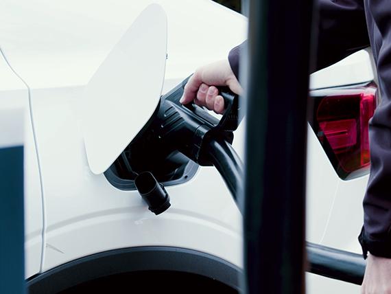 Someone filling up their EV battery holding a plug.