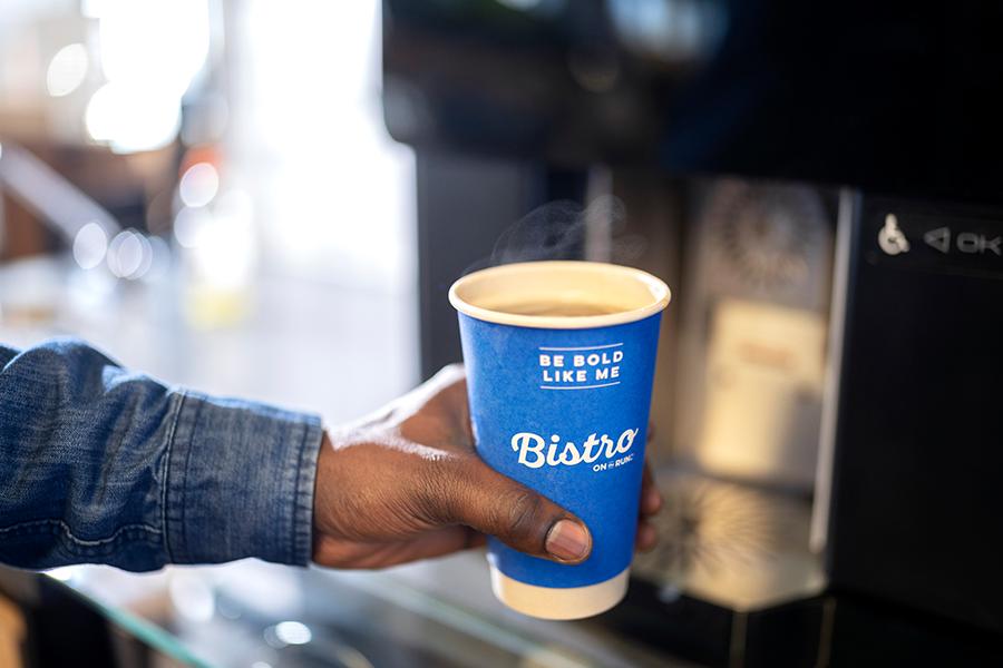 Hand holding a Bistro coffee cup filling up with coffee.