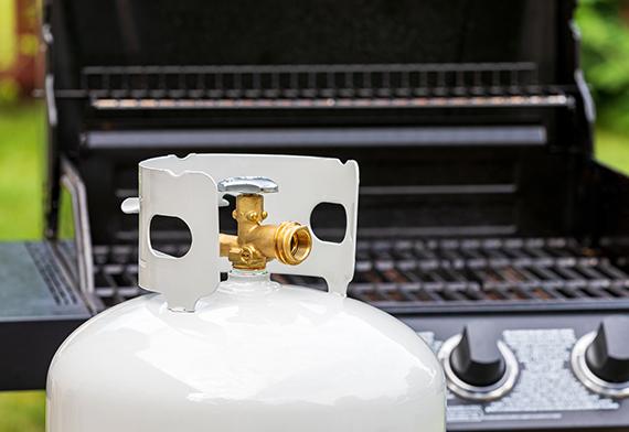 Propane cannister sitting in front of BBQ.