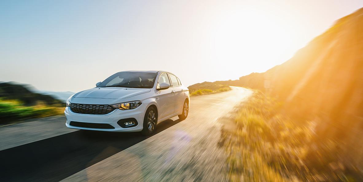 Véhicule blanc circulant sur une route à côté d'une colline.